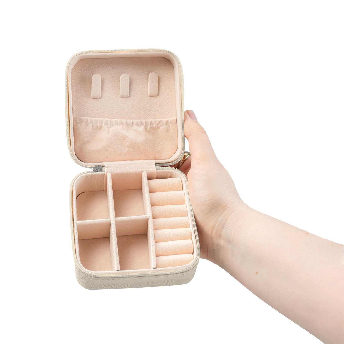 Beige jewelry box with multiple compartments held open in a hand.