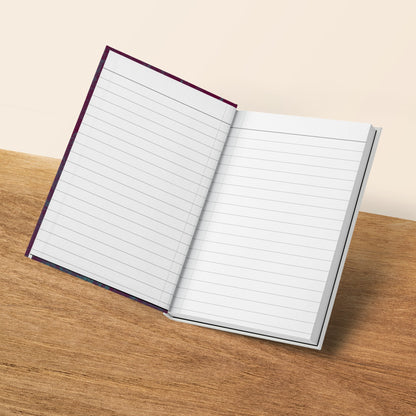 Open lined notebook with a dark patterned cover on a wooden surface.